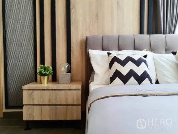 Condominium for rent or sale in Watthana, Bangkok - Cozy bedroom corner with upholstered headboard, chevron pillows and wooden nightstand.