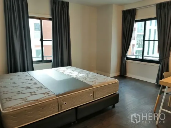 อพาร์ทเมนท์ ให้เช่าในKhlong Toei, Bangkok - ห้องนอนกว้างมีหน้าต่างสองบาน ผ้าม่านสีเทา และฐานรองที่นอน