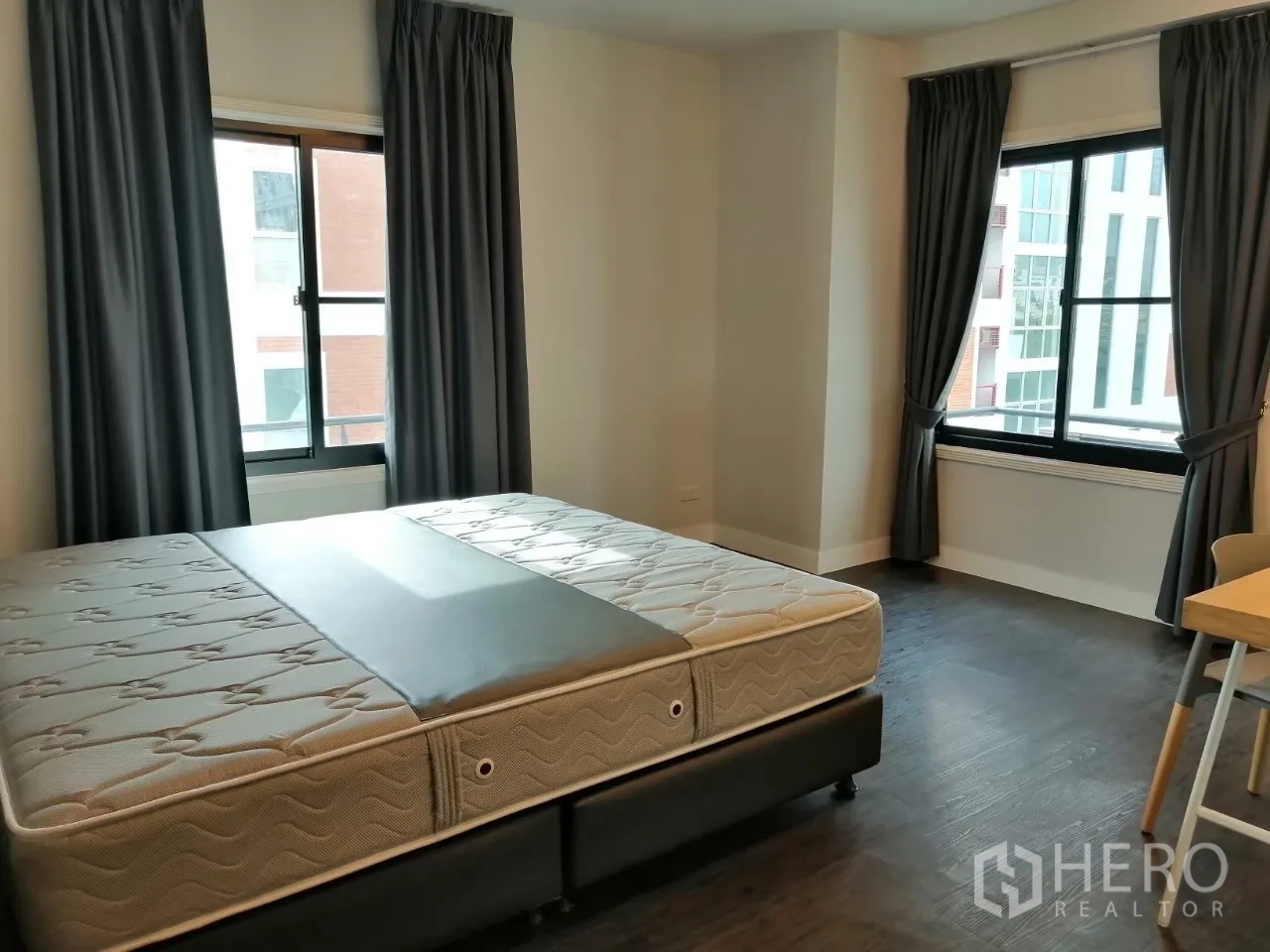 อพาร์ทเมนท์ ให้เช่าในKhlong Toei, Bangkok - ห้องนอนกว้างมีหน้าต่างสองบาน ผ้าม่านสีเทา และฐานรองที่นอน