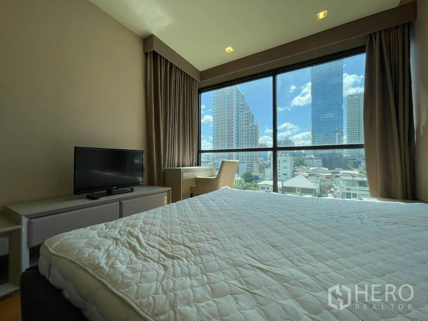 Condominium for rent or sale in Bang Rak, Bangkok - Bedroom with TV console, desk by the window and skyline outlook.
