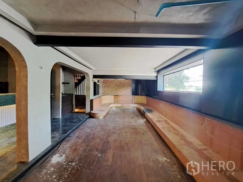 零售空间 出租在Watthana, Bangkok - 二层宽敞区域，内置长条卡座、木地板、砖墙与横向大窗。