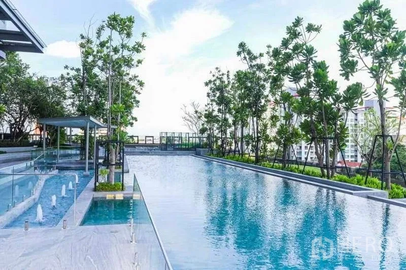 Condominium for rent in Phra Khanong, Bangkok - Outdoor swimming pool lined with trees, glass fencing and city views.