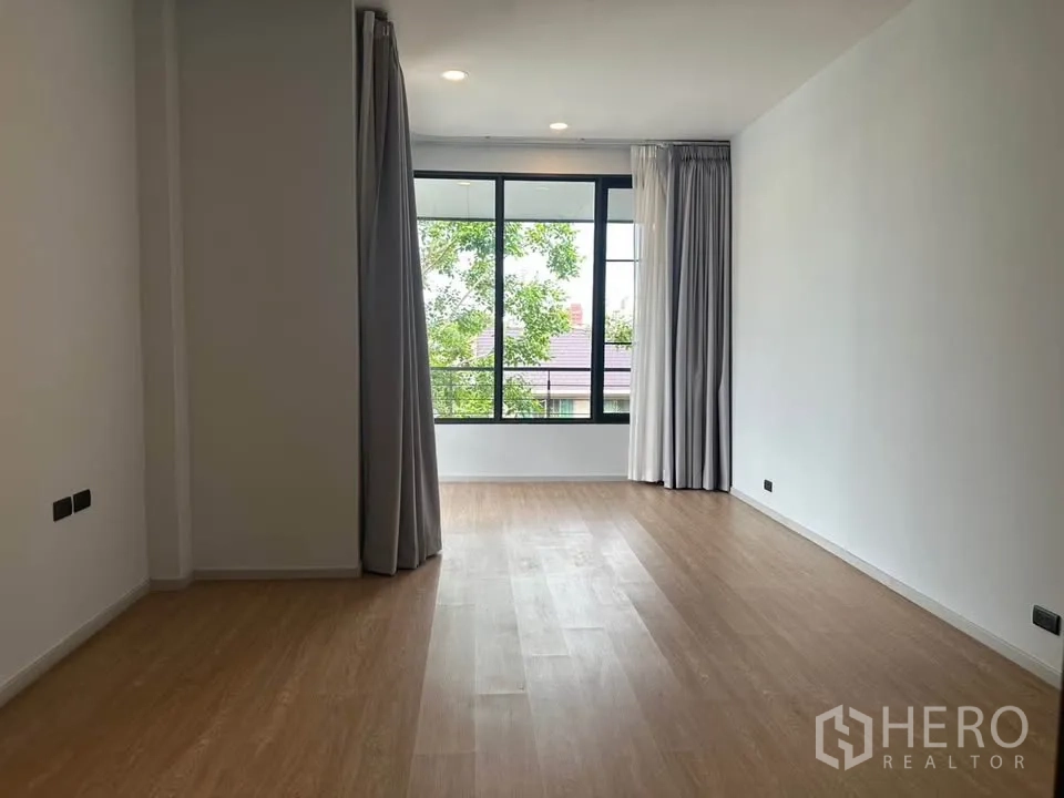 Detached House for sale in Watthana, Bangkok - Sunlit bedroom with a wide window and curtains.