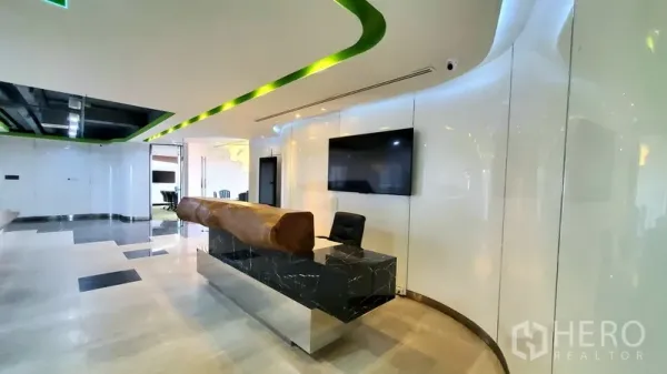 办公空间 出租在Watthana, Bangkok - 现代化接待区，配大理石前台、弧形灯带天花与壁挂屏幕。