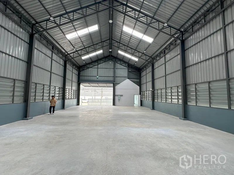Factory for rent in Khlong Luang, Pathum Thani - Long clear-span warehouse looking toward the entrance and small office cube.