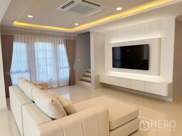 Detached House for rent or sale in Bang Phli, Samut Prakan - Living area with built-in TV wall, staircase and cove lighting.
