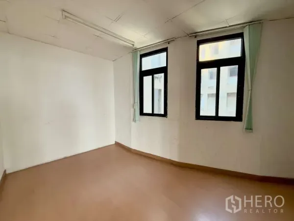 办公空间 出租在Chatuchak, Bangkok - 小型办公室，两扇高窗配窗帘，中性色墙面与木纹地面。