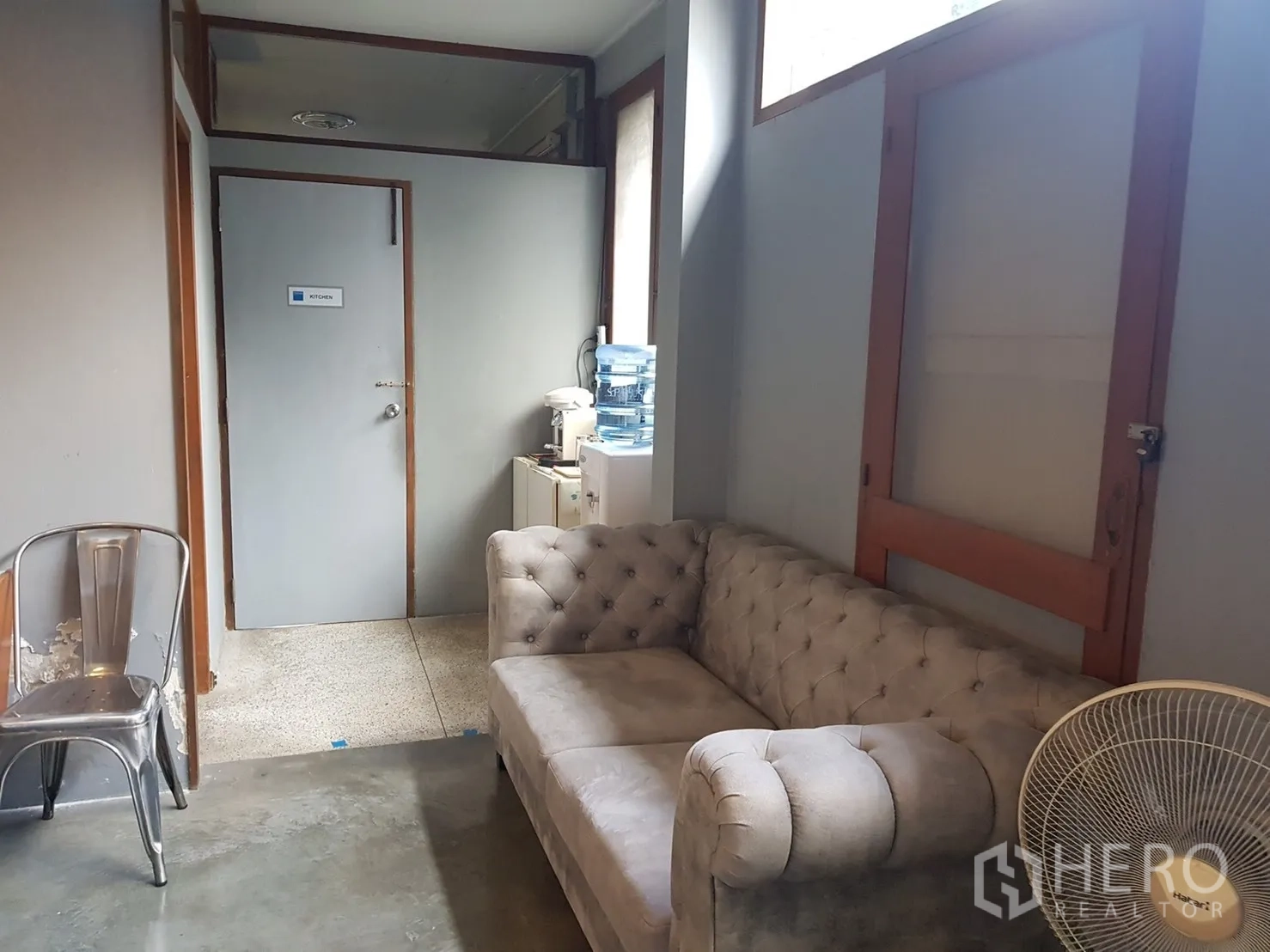 Home Office for rent in Watthana, Bangkok - Cozy lounge area with tufted sofa beside a small pantry and utility door.