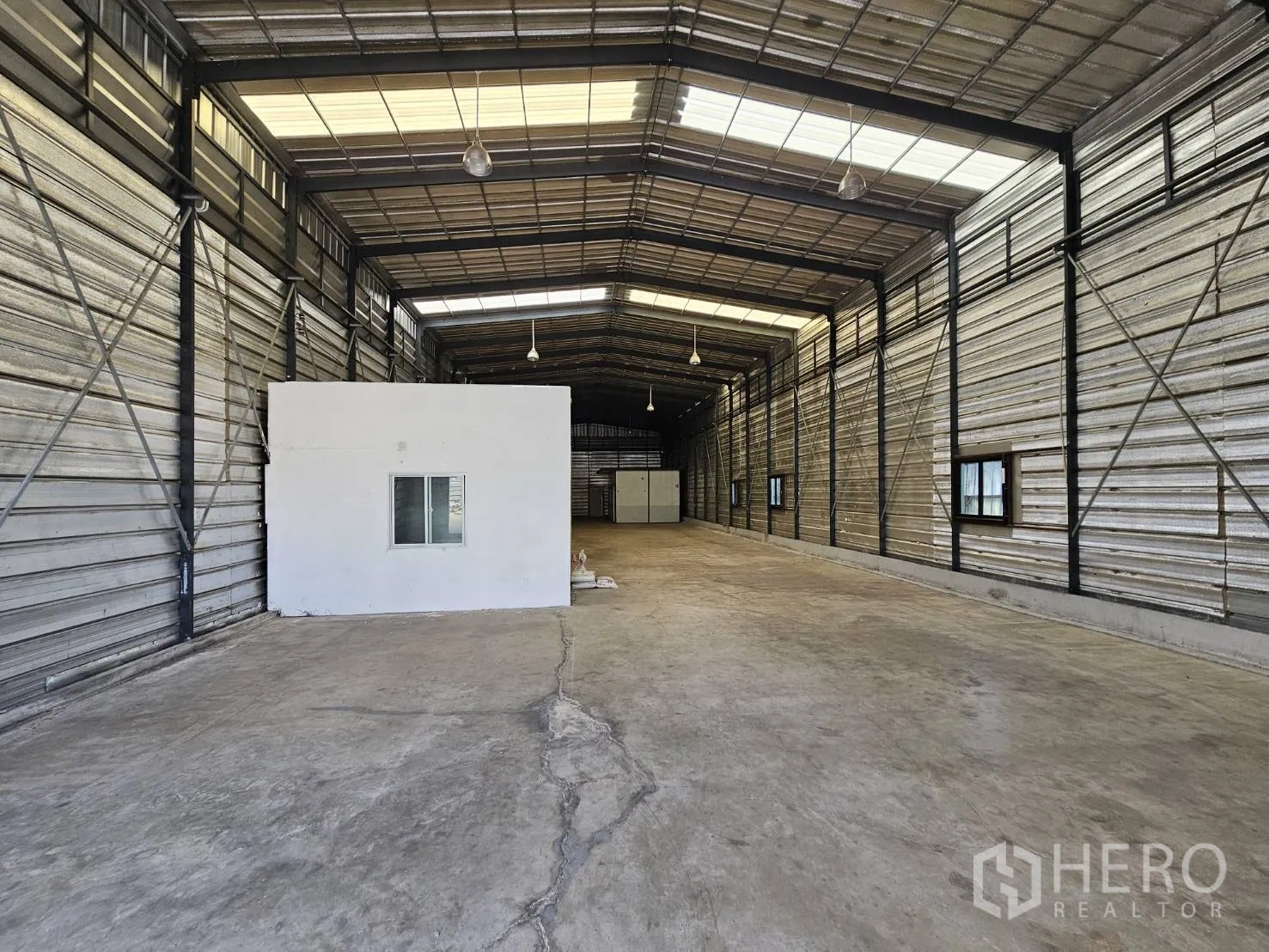 Warehouse for rent in Bang Phli, Samut Prakan - Front section of the warehouse showing concrete floor, ventilation windows, and an internal office block.