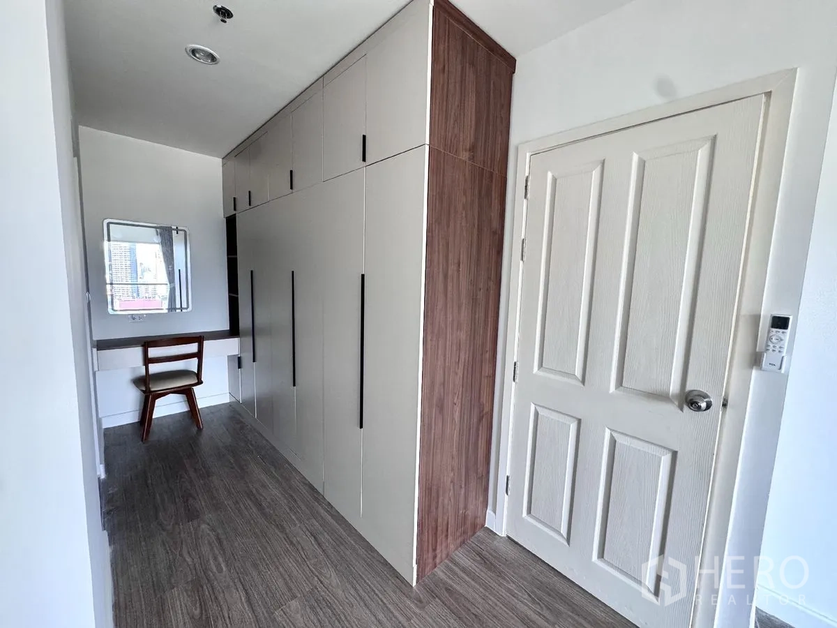 Condominium for rent in Huai Khwang, Bangkok - Hallway with full-height wardrobes and a small dressing table with chair.