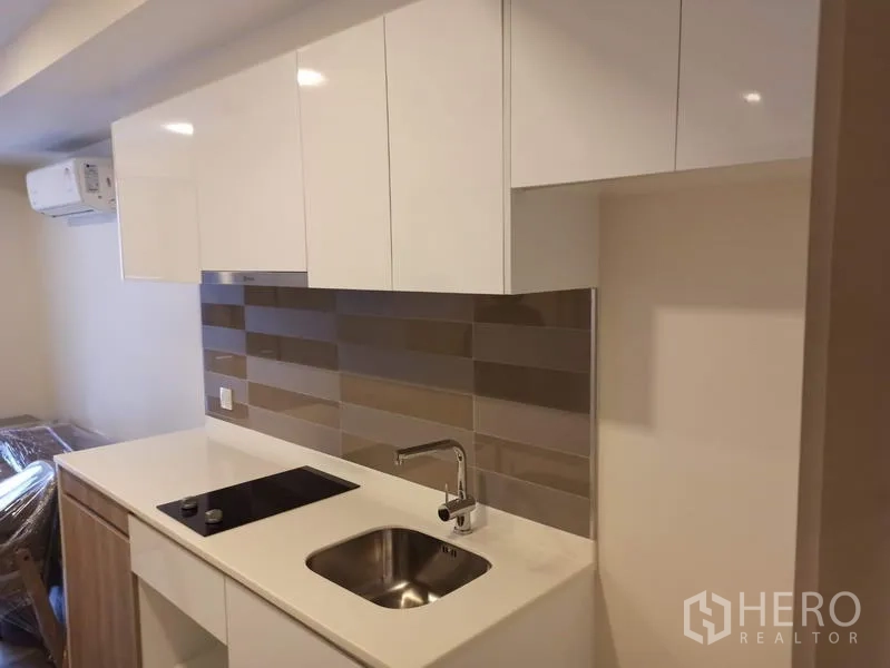 คอนโด ขายในDin Daeng, Bangkok - ครัวขนาดกะทัดรัด ตู้หน้าบานขาว เตาไฟฟ้า อ่างล้างจาน และผนังกระเบื้องลายเส้น ในคอนโดมาเอสโตร 03