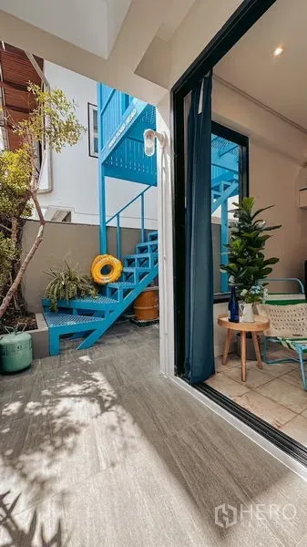 Home Office for rent in Watthana, Bangkok - Small patio with gray tiles and an external blue metal staircase beside a glass door.