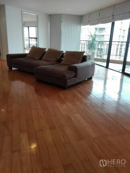 คอนโด ให้เช่าในKhlong Toei, Bangkok - ห้องนั่งเล่นอีกมุมพร้อมโซฟาตัวแอล หน้าต่างกระจกโดยรอบและทางออกสู่ระเบียง