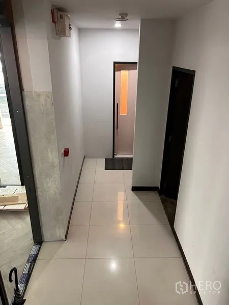 Office Space for rent in Khlong Toei, Bangkok - Clean interior corridor with glossy tiled floor, side doors and a lit glass door at the end.