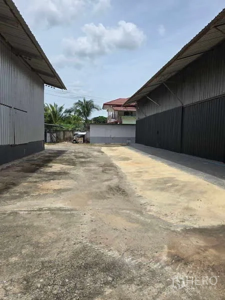 Warehouse for rent in Khlong Sam Wa, Bangkok - Driveway between two warehouse sheds leading to a rear yard.