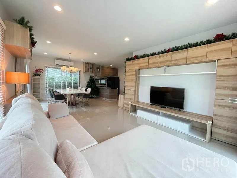 独立式住宅 出售在Pak Kret, Nonthaburi - 明亮客厅，内置电视墙，连接厨房与用餐区。