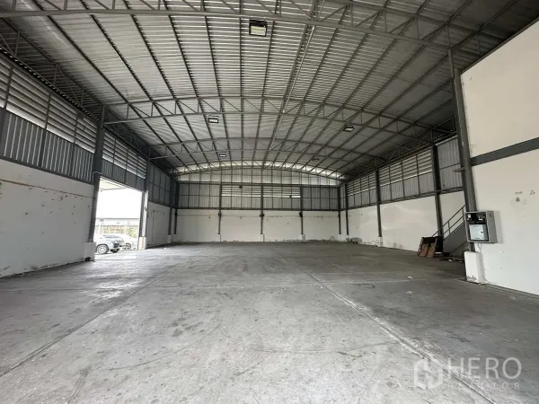 Factory for rent in Pathum Thani - Warehouse interior toward back wall showing side access door and steel staircase.