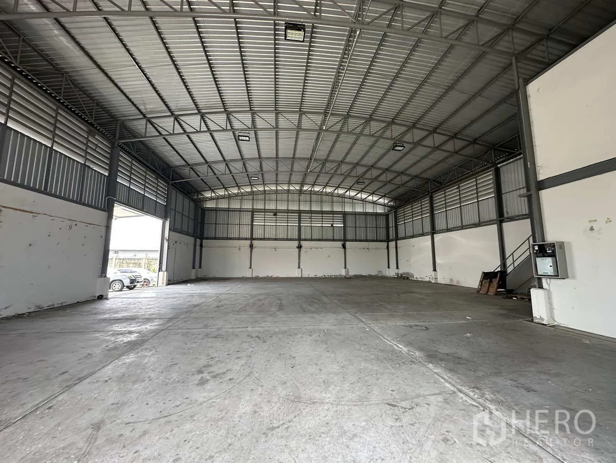 Factory for rent in Pathum Thani - Warehouse interior toward back wall showing side access door and steel staircase.