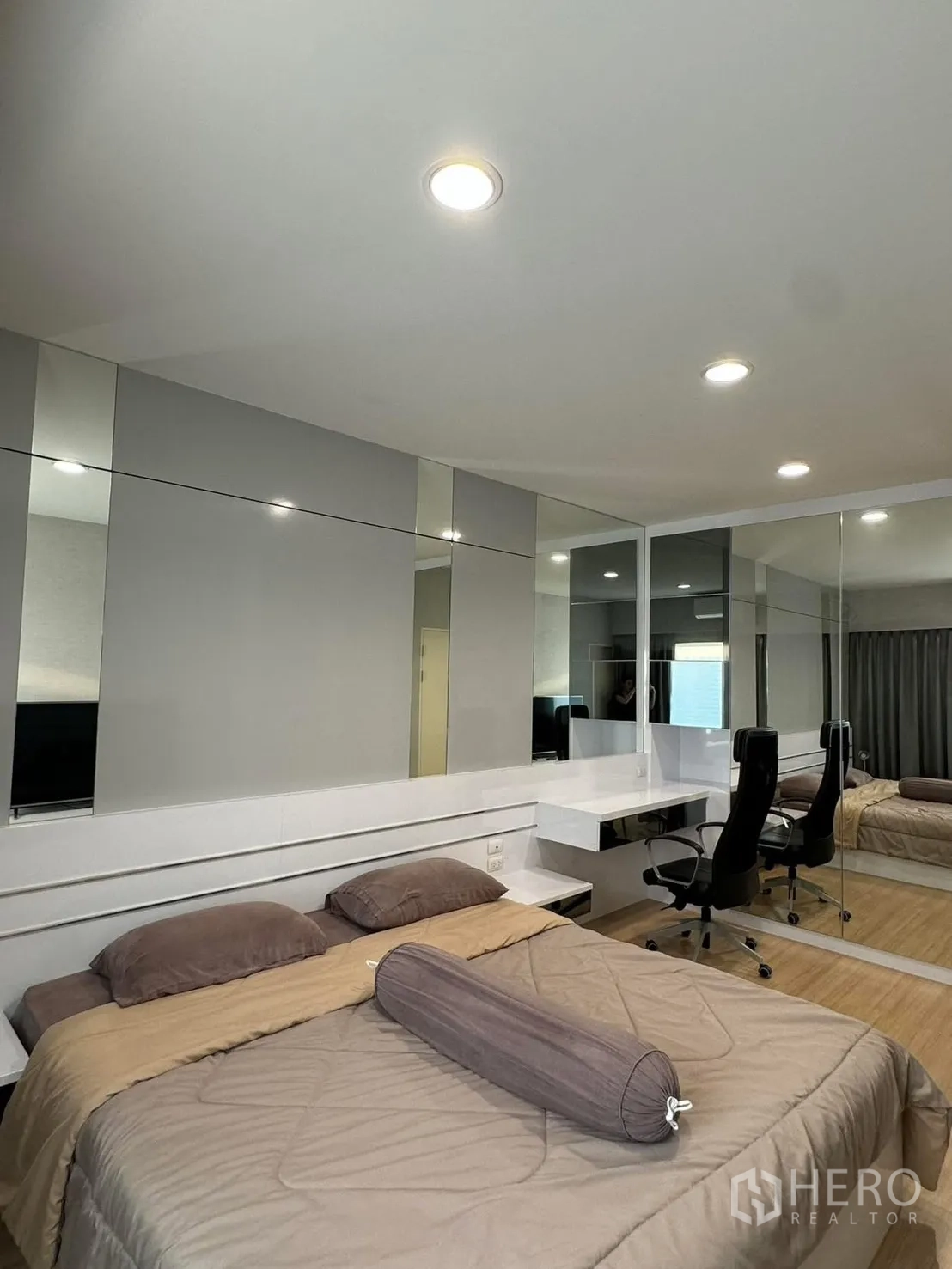 联排别墅 for rent in Suan Luang, Bangkok - 卧室角度展示镜面墙、内置床头与带椅的书桌。