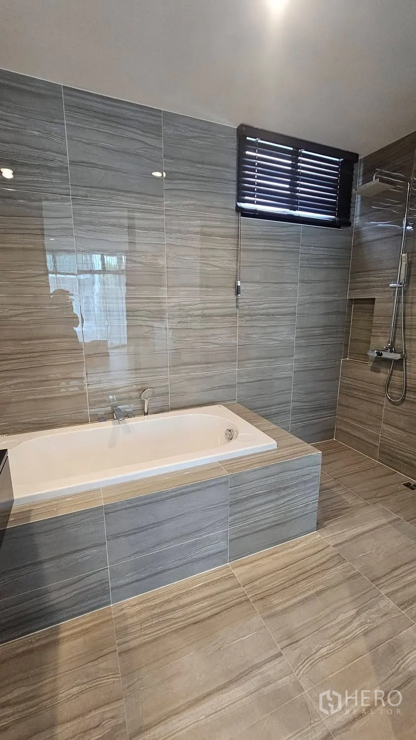Townhouse for rent in Saphan Sung, Bangkok - Modern bathroom with soaking bathtub, separate shower, and gray wall tiles.