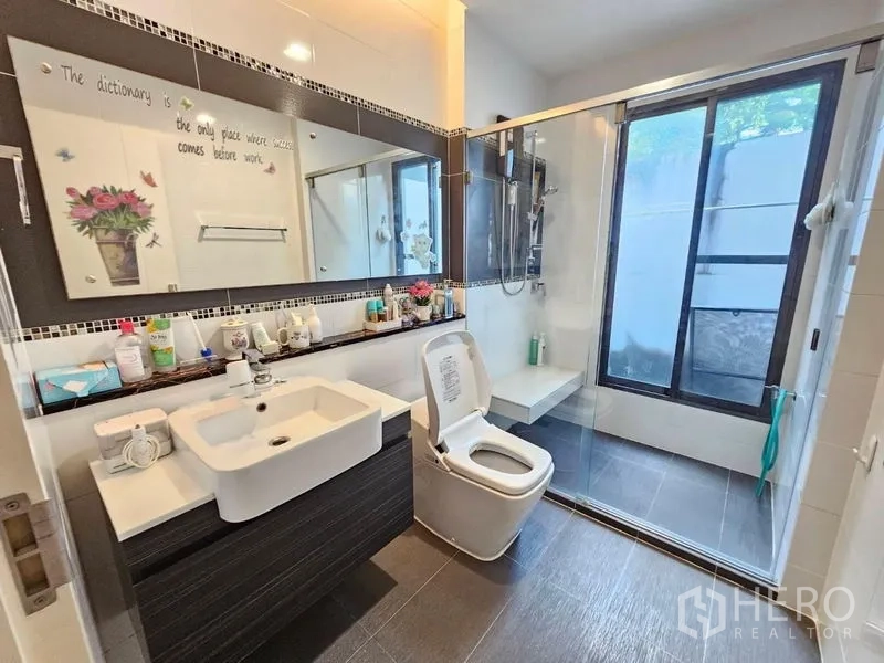 Detached House for sale in Prawet, Bangkok - Main bathroom featuring vanity, toilet and large glass shower with bench and window.