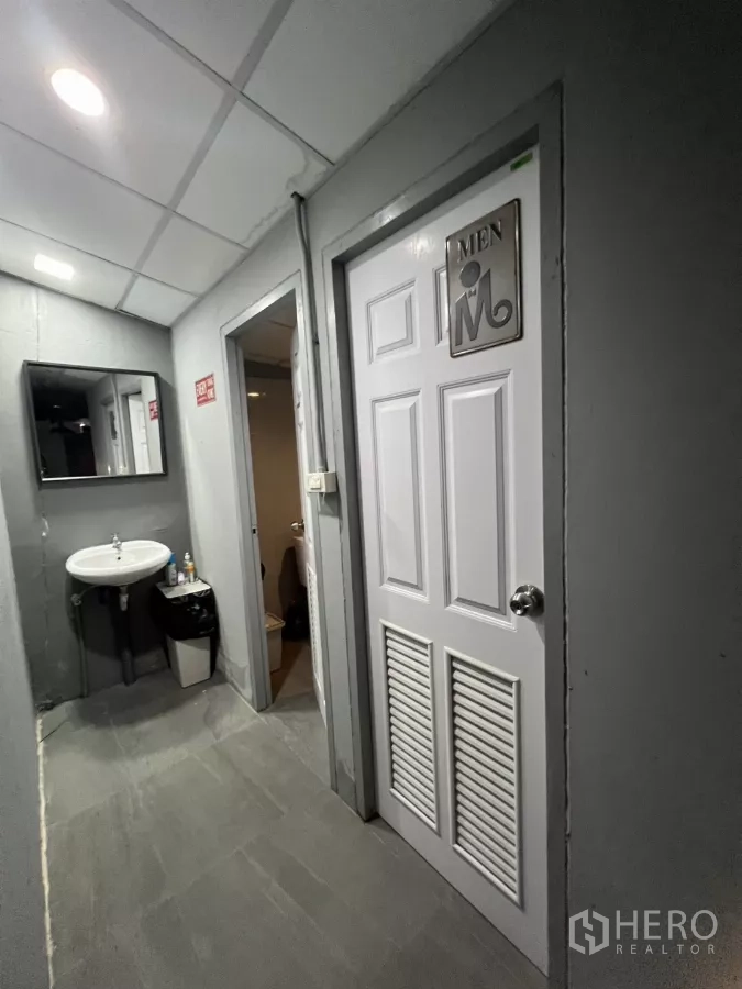 零售空间 出租在Watthana, Bangkok - 走廊设男卫标识门与洗手池。