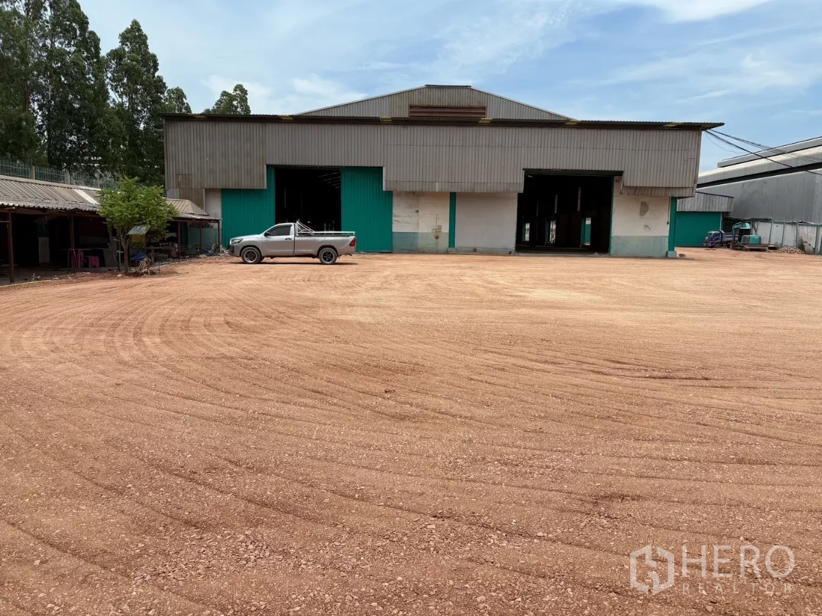 工厂 出租在Mueang Samut Sakhon, Samut Sakhon - 厂房正面与一辆皮卡及大片夯实院场，适合大车出入。