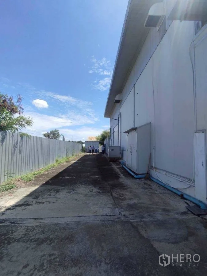 Factory for rent or sale in Mueang Nakhon Pathom, Nakhon Pathom - Side driveway along the factory with fencing and service access.