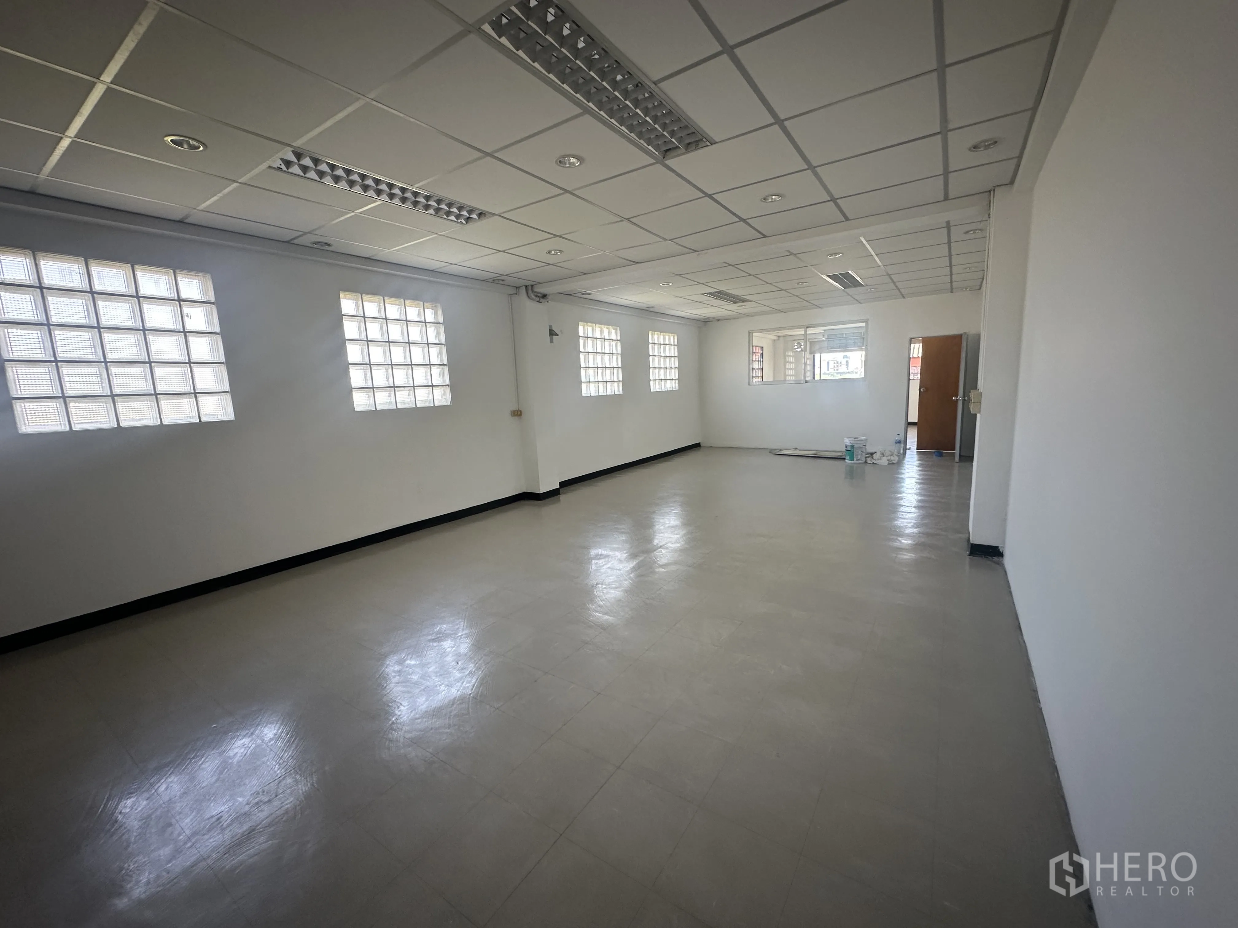 Office Space for rent in Watthana, Bangkok - Open office area featuring multiple glass-block windows, suspended ceiling lights and clean vinyl floors.