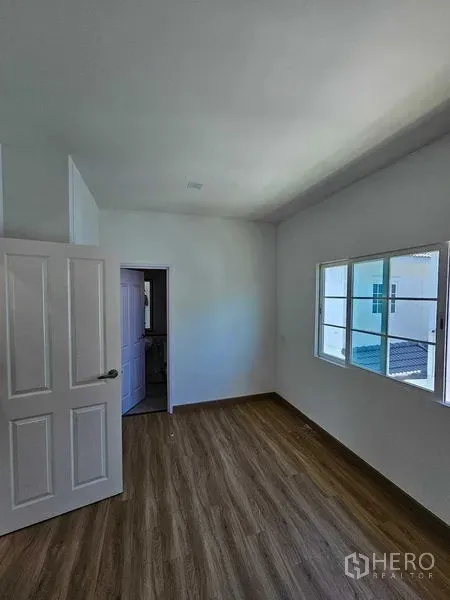 Detached House for rent in Thanyaburi, Pathum Thani - Bright bedroom with wood-look flooring, white walls and a window