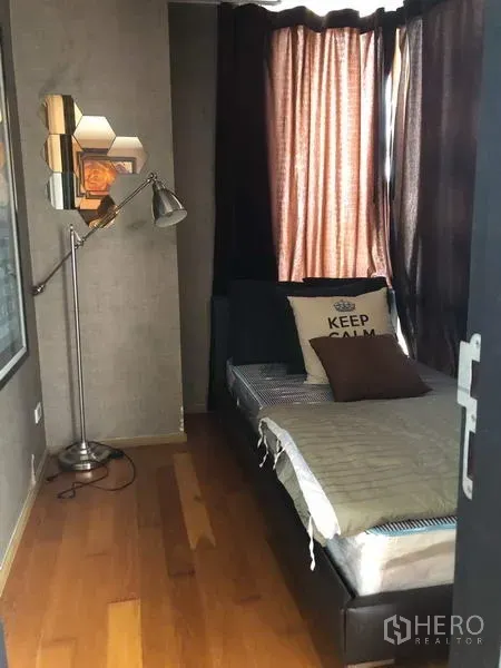 Condominium for rent in Pathum Wan, Bangkok - Compact multipurpose room with single bed, floor lamp and blackout curtains.