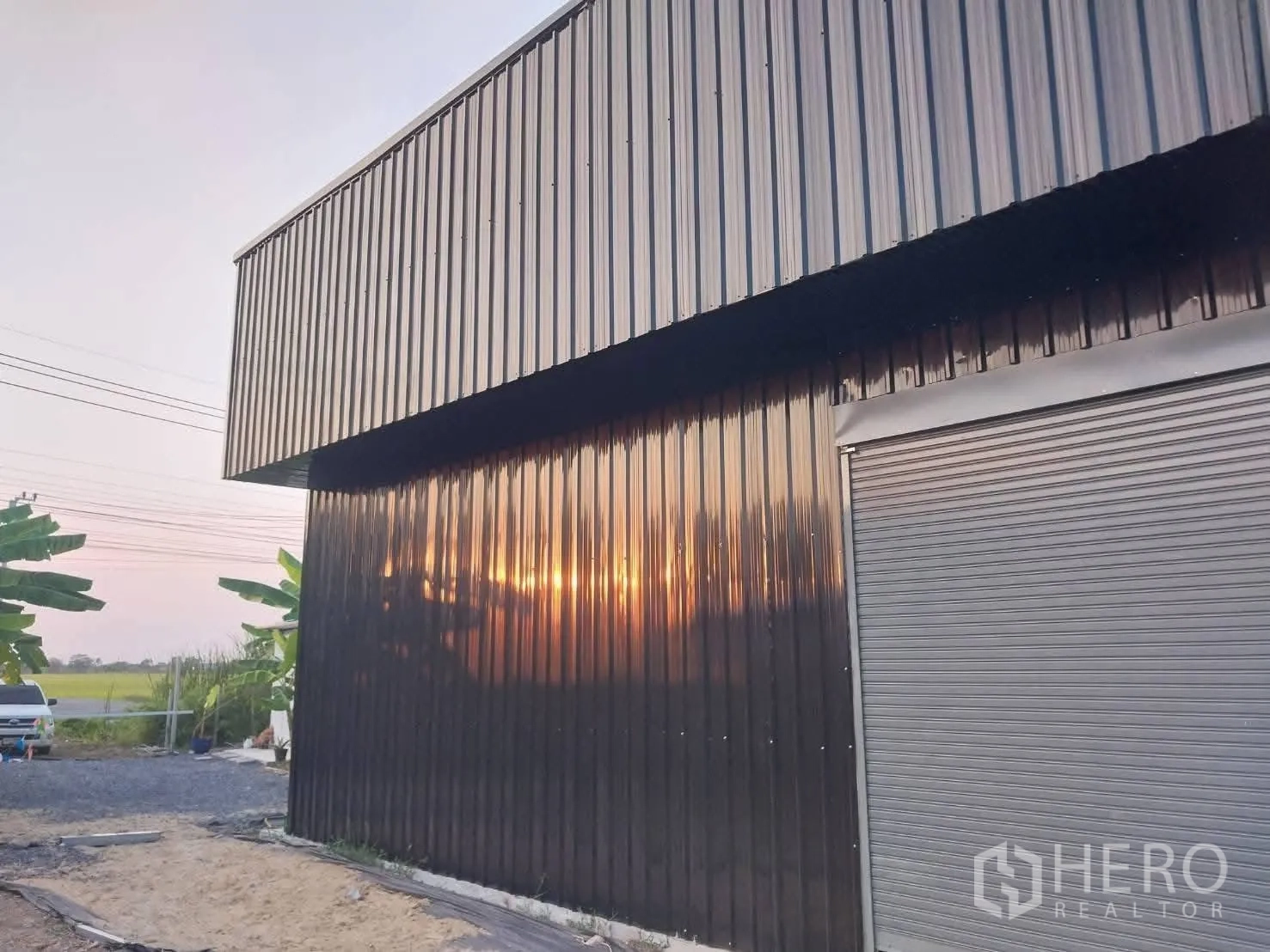 Warehouse for rent in Lat Krabang, Bangkok - Side view of the warehouse exterior with a roller door and driveway.