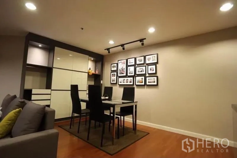 Condominium for rent in Huai Khwang, Bangkok - Dining area for four with track lighting, built-in cabinetry and a gallery photo wall.