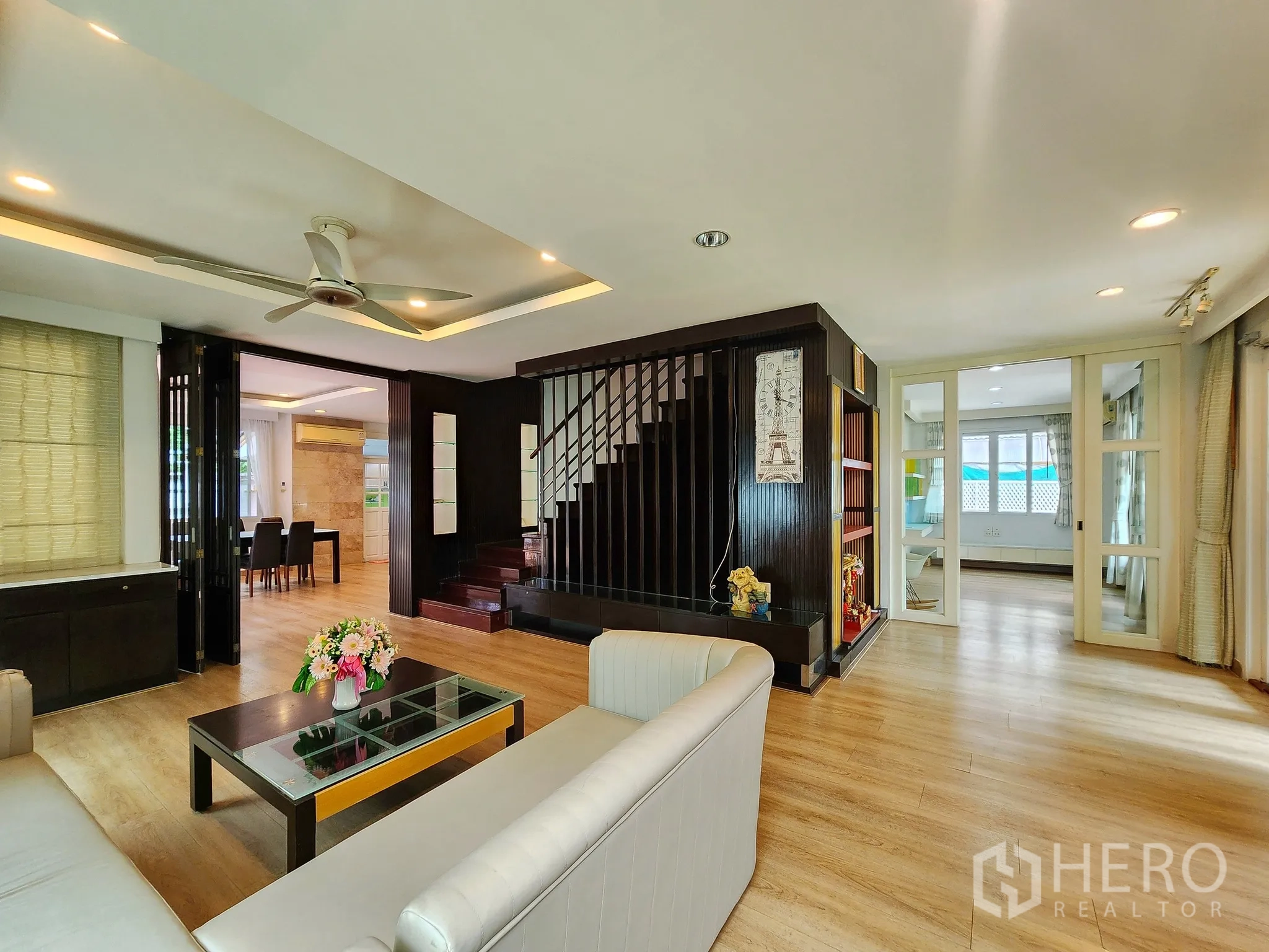 独立式住宅 出租在Bang Kapi, Bangkok - 客厅相连深色木楼梯与餐区的开放格局。