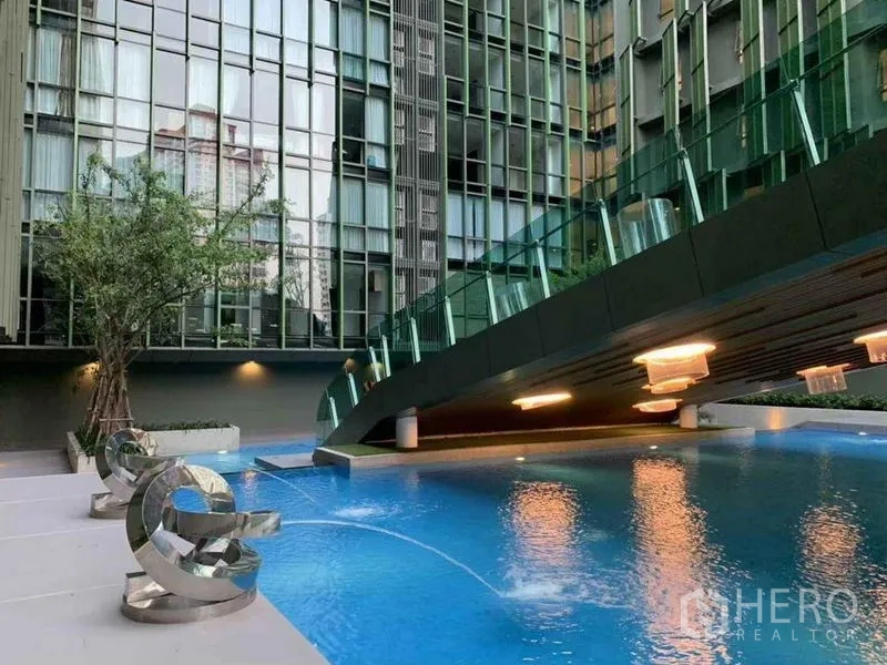 Condominium for sale in Ratchathewi, Bangkok - Modern condominium pool with elevated sky-bridge and sculptural seating in Ratchathewi, Bangkok.