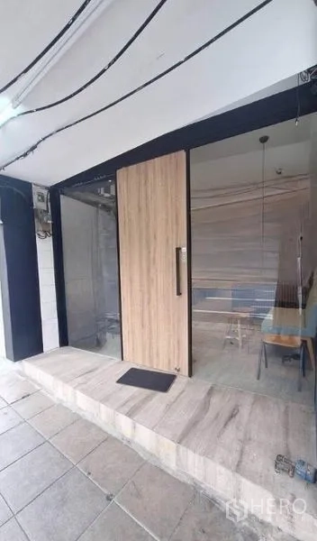 พื้นที่ขายปลีก ให้เช่าในWatthana, Bangkok - ทางเข้าร้านกระจกพร้อมประตูไม้และลานปูกระเบื้องด้านหน้า เหมาะติดป้าย