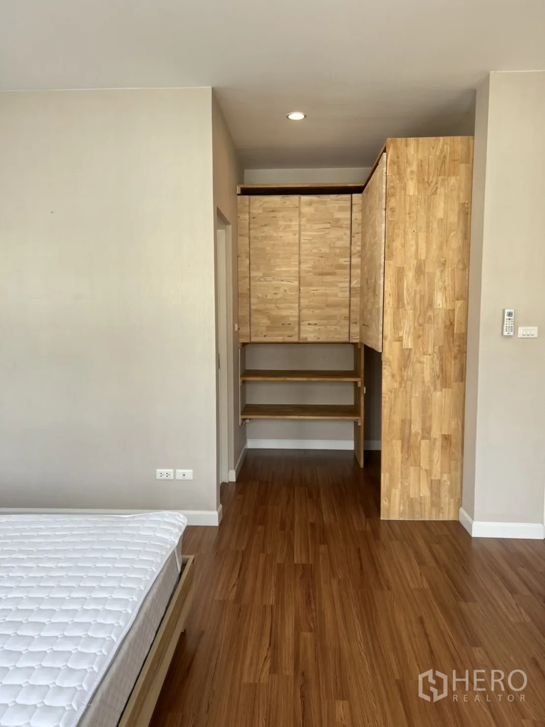 Detached House for rent in Bang Kapi, Bangkok - Bedroom with built‑in wooden wardrobe, open shelving, and laminate flooring.