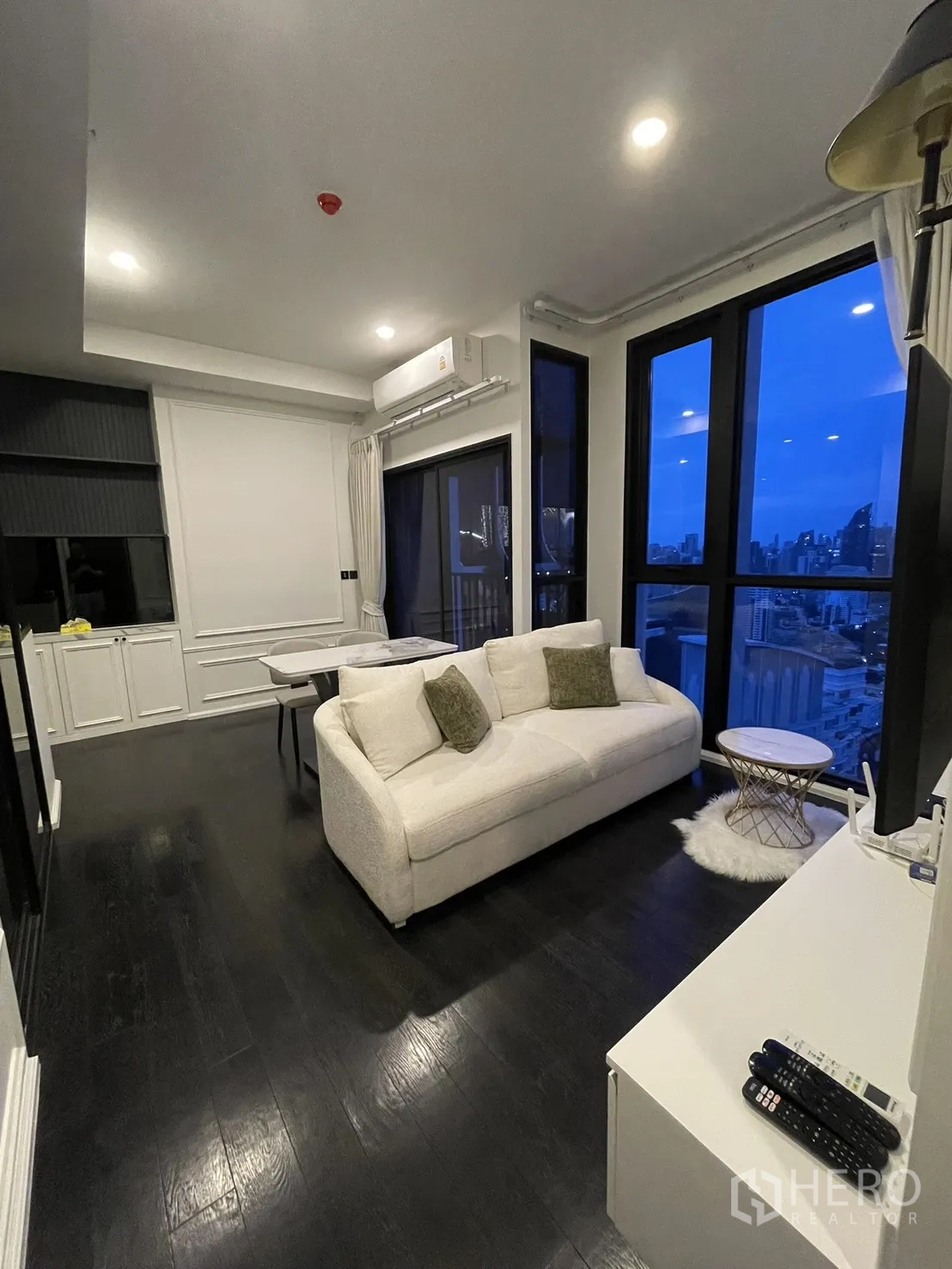 Condominium for rent in Watthana, Bangkok - Bright living room with sofa, large windows, and night cityscape.