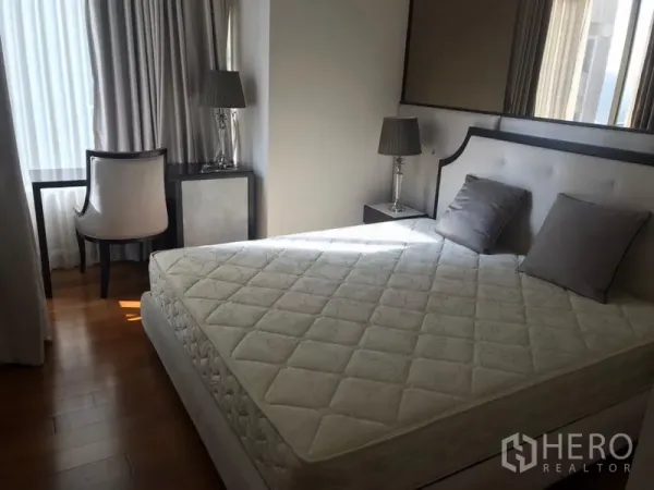 คอนโด ให้เช่าในPathum Wan, Bangkok - ห้องนอนหลักกว้างขวาง เตียงขนาดใหญ่ โต๊ะข้างเตียงพร้อมโคมไฟ โต๊ะทำงานริมหน้าต่าง และพื้นไม้