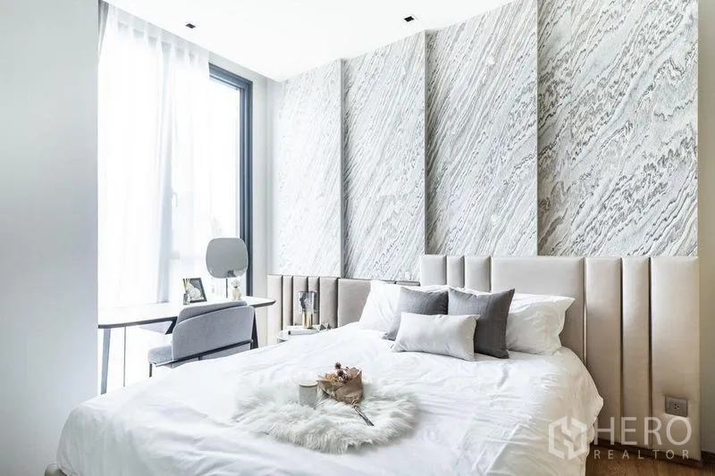 คอนโด ให้เช่าในKhlong Toei, Bangkok - ห้องนอนรองสว่างด้วยผนังลวดลายเท็กซ์เจอร์ หัวเตียงซอฟต์พาเนล และโต๊ะทำงานริมหน้าต่าง