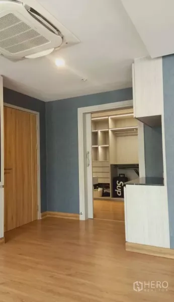 独立式住宅 出租或出售在Khan Na Yao, Bangkok - 木地板与蓝色墙面，吊顶柜机空调，通往步入式衣帽间的门。