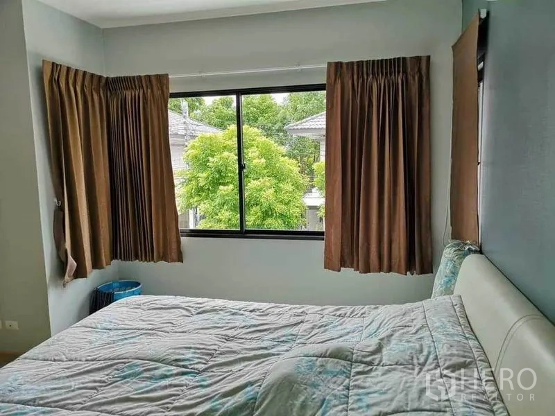 Detached House for sale in Bang Phli, Samut Prakan - Cozy bedroom with large corner windows and brown curtains overlooking greenery