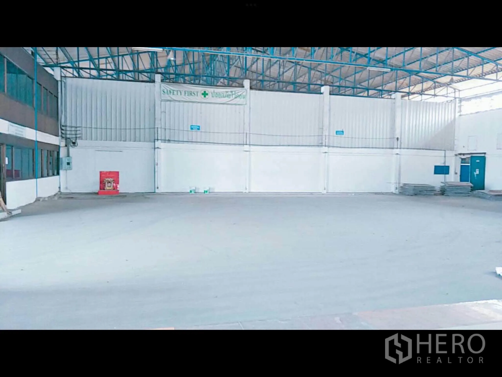 Warehouse for rent in Bang Phli, Samut Prakan - Central warehouse floor with steel trusses, lighting, and a visible safety equipment cabinet.