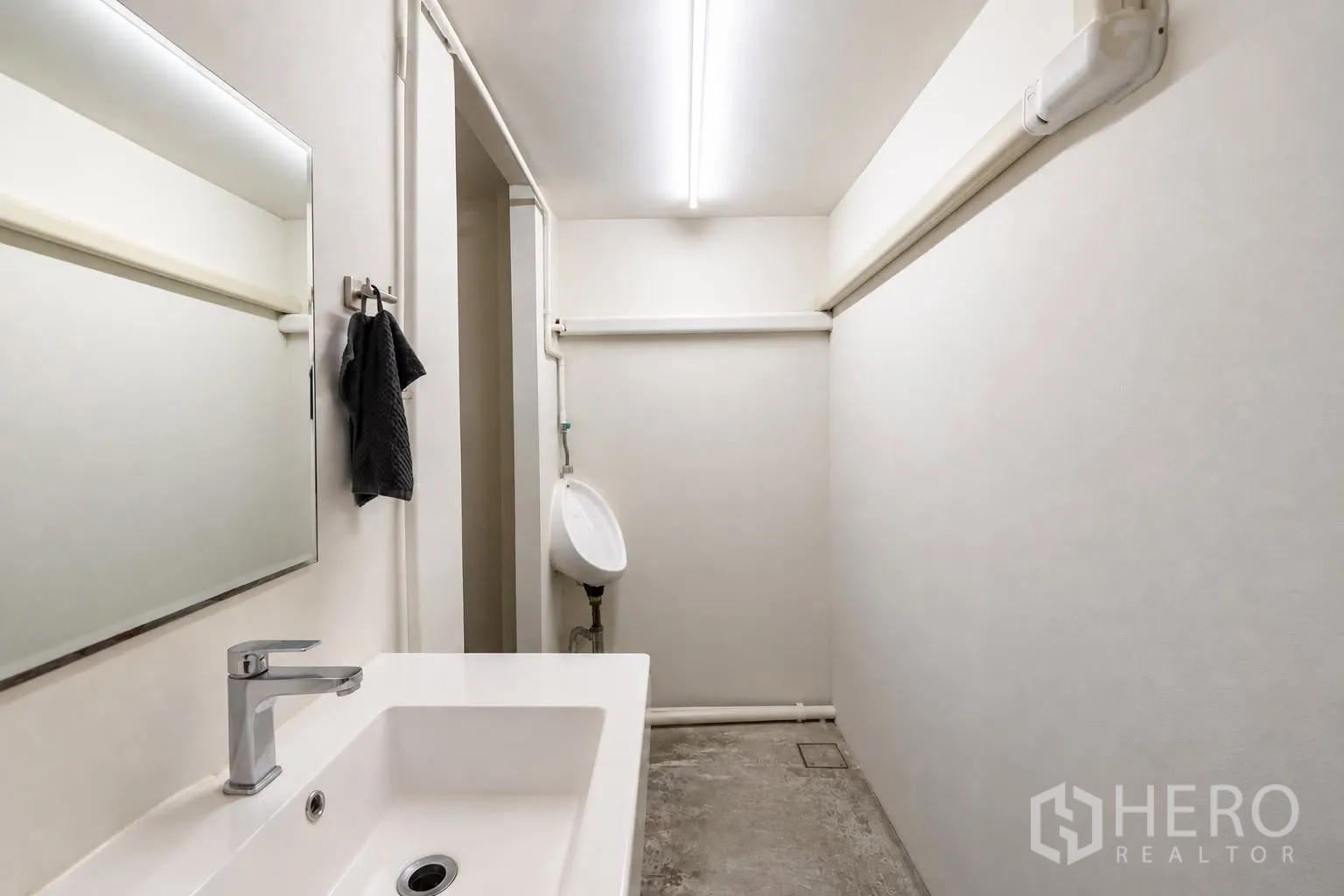 Retail Space for rent in Watthana, Bangkok - Clean restroom area with rectangular sink, mirror, and urinal under bright lighting.