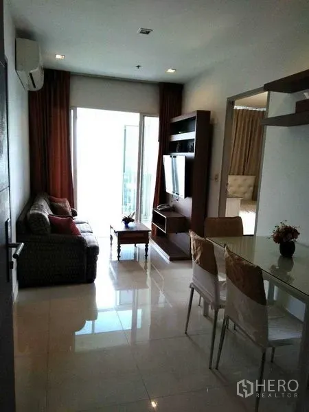 Condominium for rent in Watthana, Bangkok - Living and dining area opening to a bright balcony with natural light.