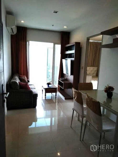 Condominium for rent in Watthana, Bangkok - Living and dining area opening to a bright balcony with natural light.