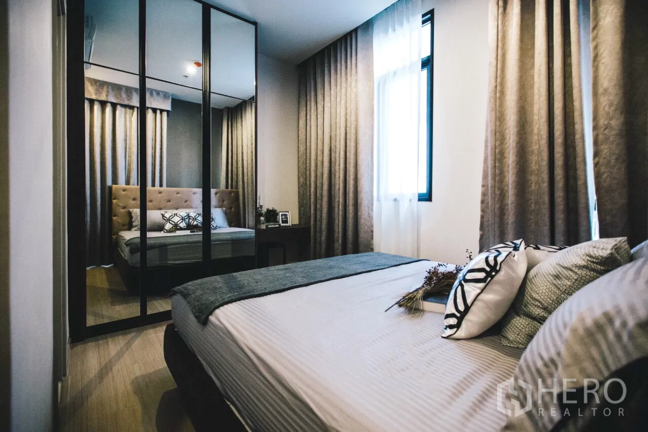 Condominium for rent in Huai Khwang, Bangkok - Secondary bedroom with large mirrored closet, soft curtains, and natural light.