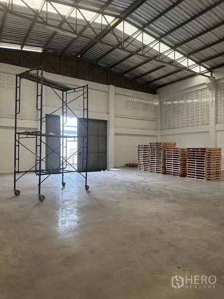 货栈 出租在Suan Luang, Bangkok - 宽敞仓库内部，高挑钢结构屋顶、混凝土地面与大型滑动装卸门。