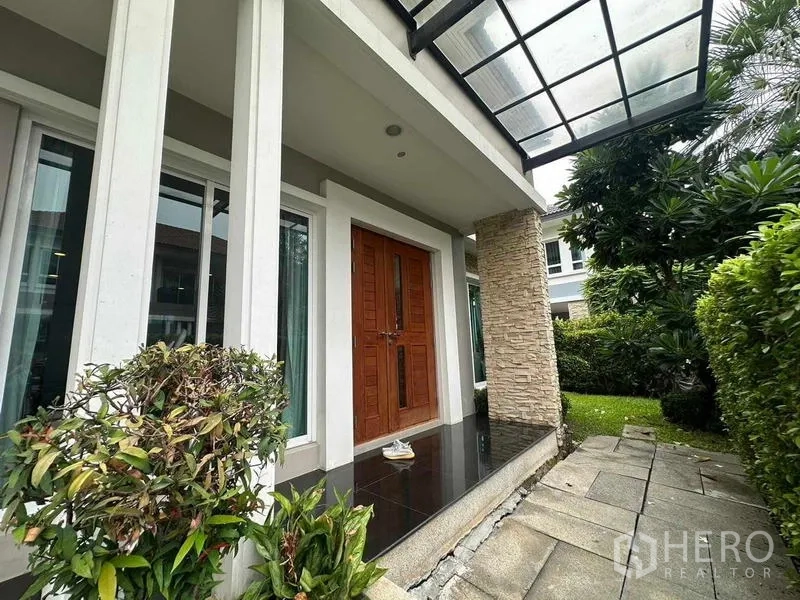 Detached House for sale in Saphan Sung, Bangkok - Covered front porch with double wooden doors and a stone pillar beside the garden.