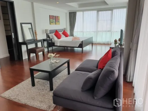 Apartment for rent in Bang Rak, Bangkok - Bright master suite with sofa, bed and floor-to-ceiling windows over hardwood floors.